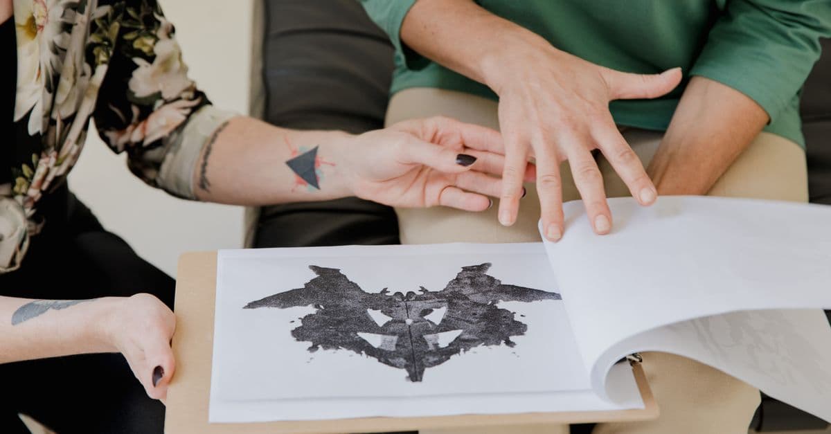 Close-up of two women discussing a Rorschach inkblot test during a therapy session.