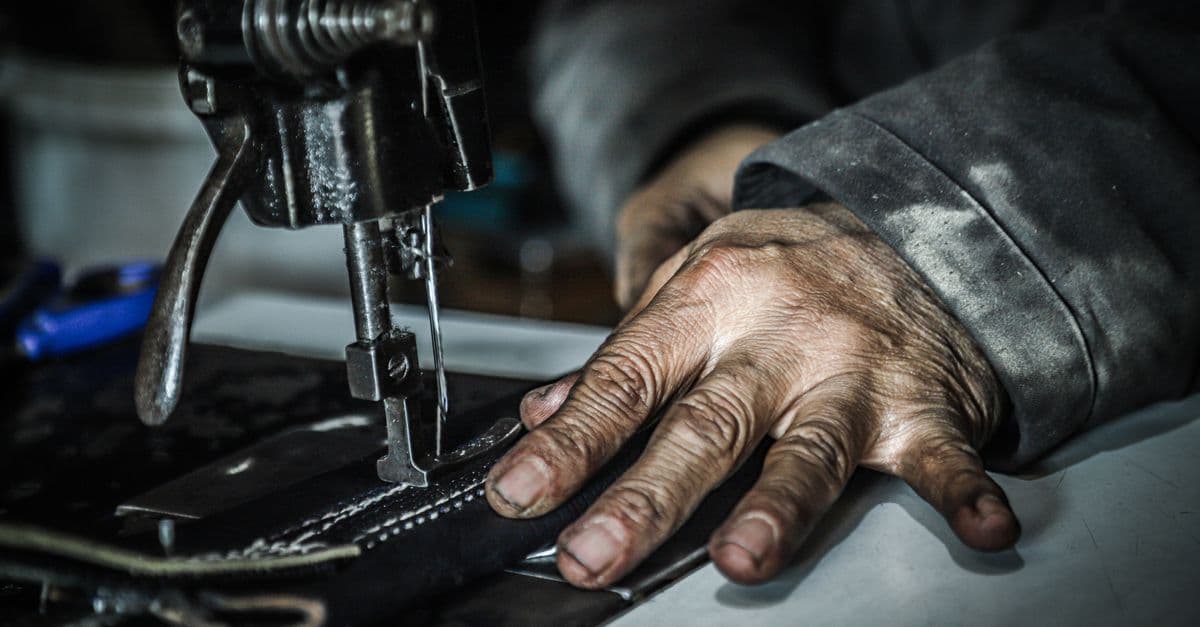 Detailed capture of hands working with a sewing machine, showcasing craftsmanship and textile work.