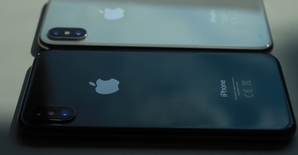 Close-up of two smartphones displayed on a table in muted lighting, showcasing sleek design.