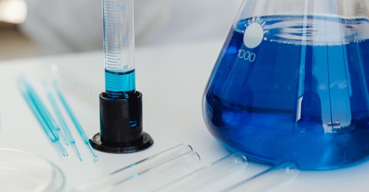 Detailed close-up of laboratory equipment including test tubes and Erlenmeyer flask with blue liquid.