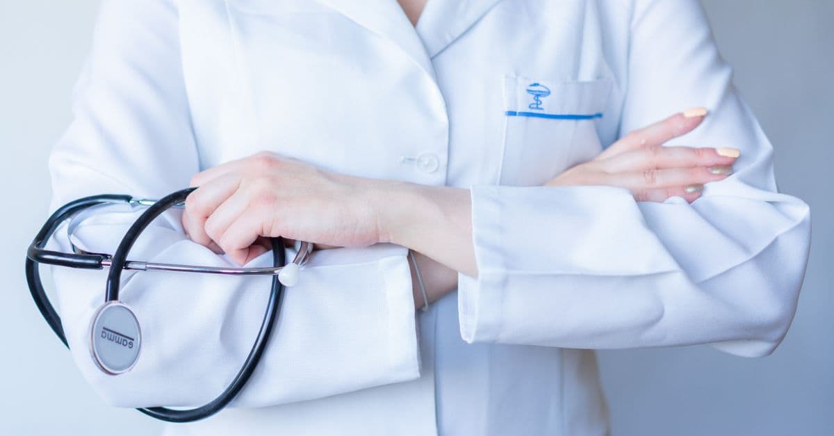A close-up image of a doctor in a white coat with a stethoscope and arms crossed.