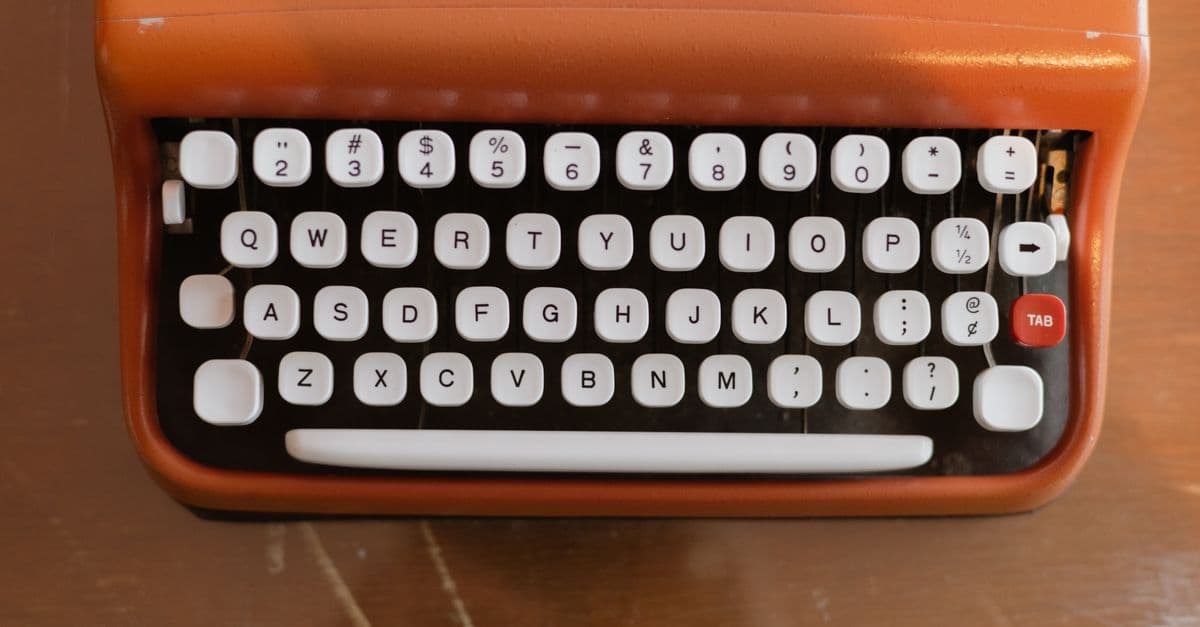 Close-up of a classic orange typewriter, highlighting retro design on a wooden surface.