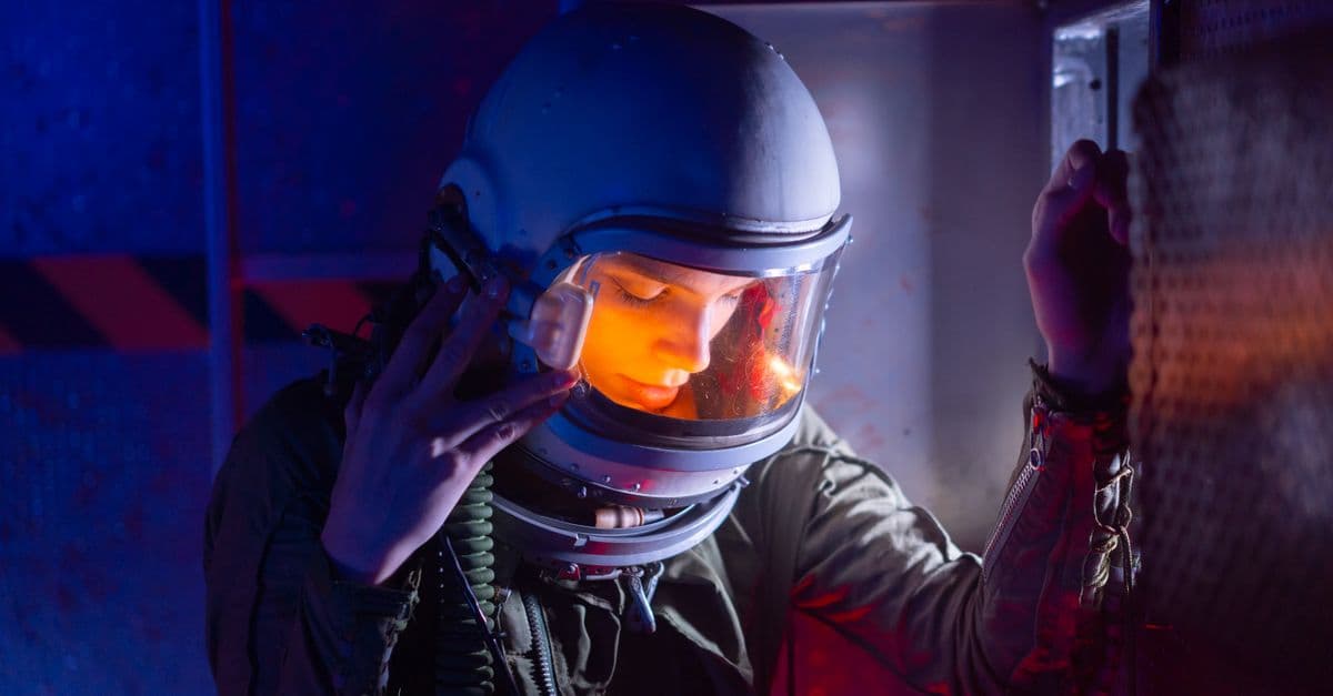 A woman astronaut in a helmet reflecting during an interstellar mission.