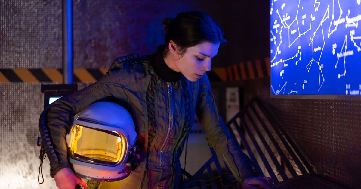 Woman astronaut in futuristic setting examining a digital star chart.