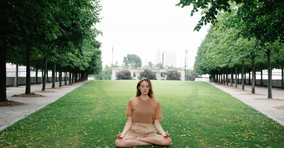 Woman practicing yoga meditation in a peaceful green park setting