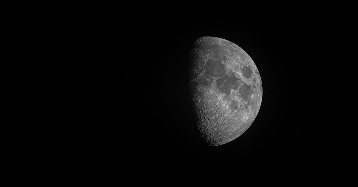 High-contrast black and white photo of a half moon in the night sky.