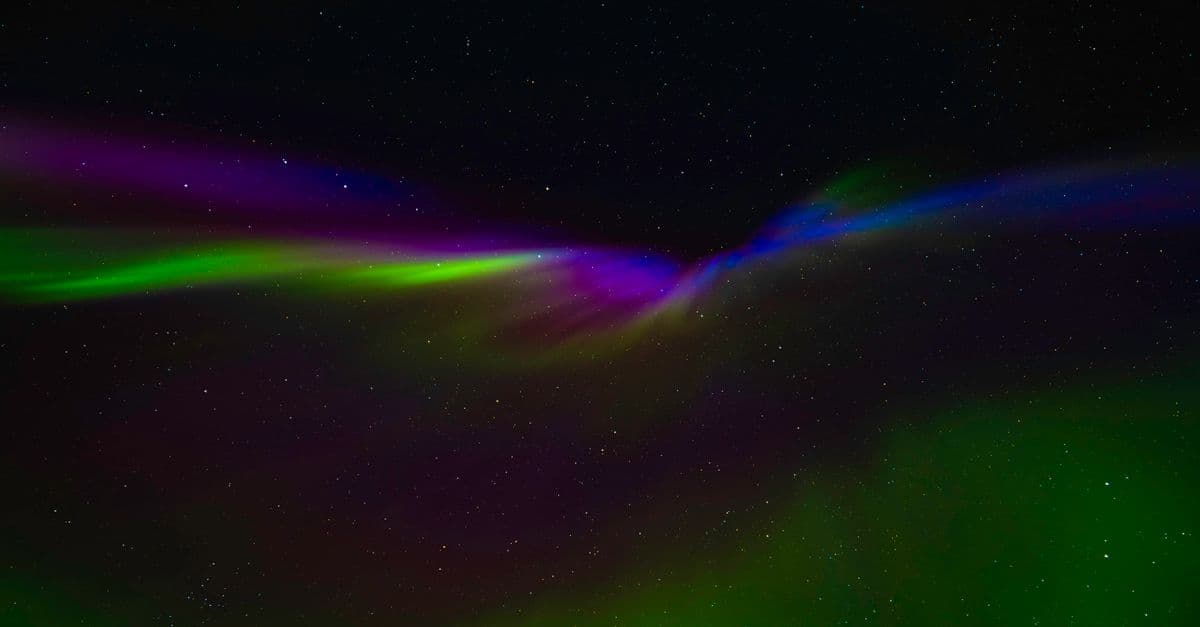 Vivid Northern Lights display in Norway's night sky, showcasing green, purple, and blue hues against starry backdrop.