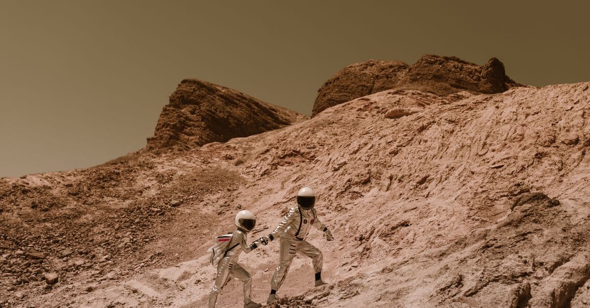 Two astronauts exploring a barren, alien landscape, resembling Mars.