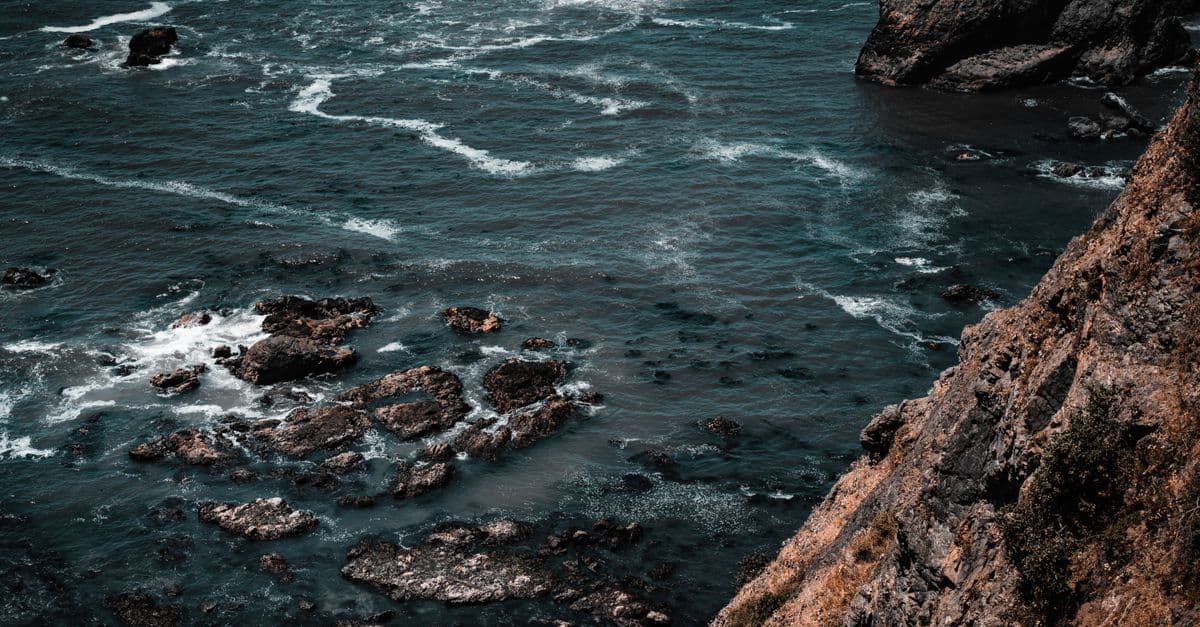 A stunning aerial view of rugged cliffs and the ocean with waves crashing against rocks.