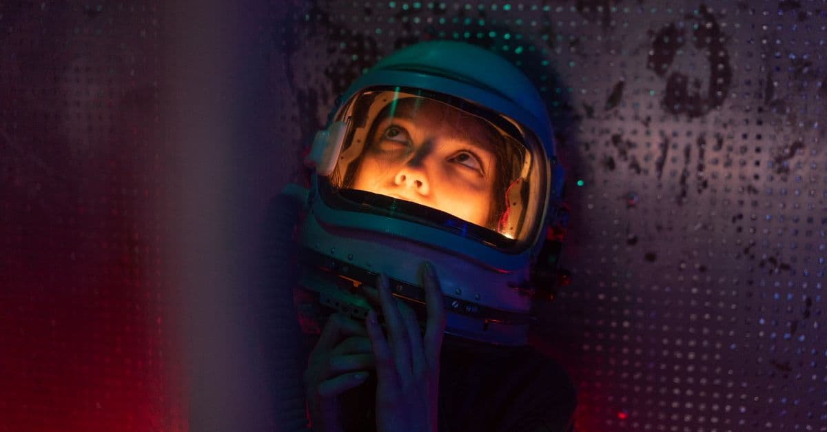 A woman in a spacesuit gazes upward, illuminated by soft, colorful lighting, creating a sci-fi atmosphere.