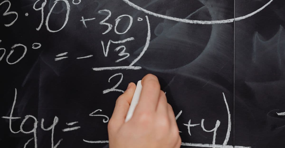 A hand vividly writing complex mathematical equations on a chalkboard.
