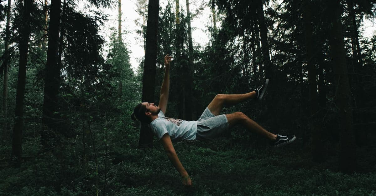 A person appears to float in a surreal scene within a lush forest setting.