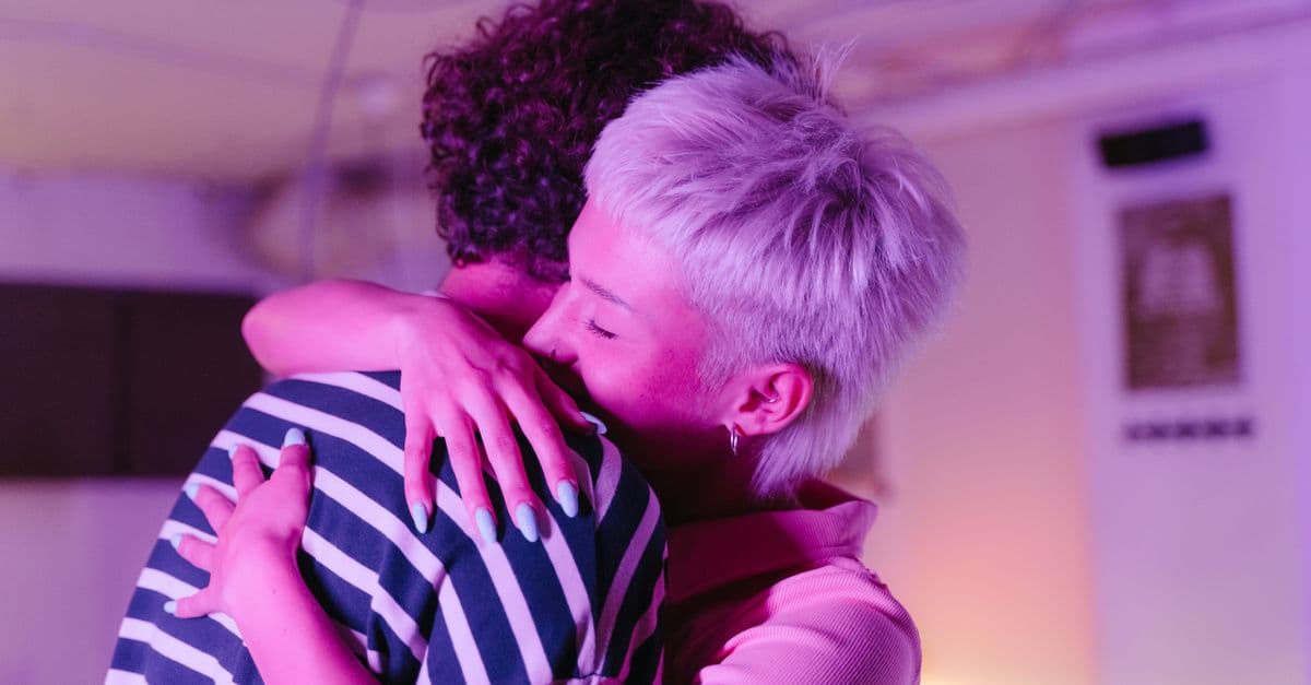 Two adults hugging warmly in a neon-lit room, creating a cozy, intimate atmosphere.