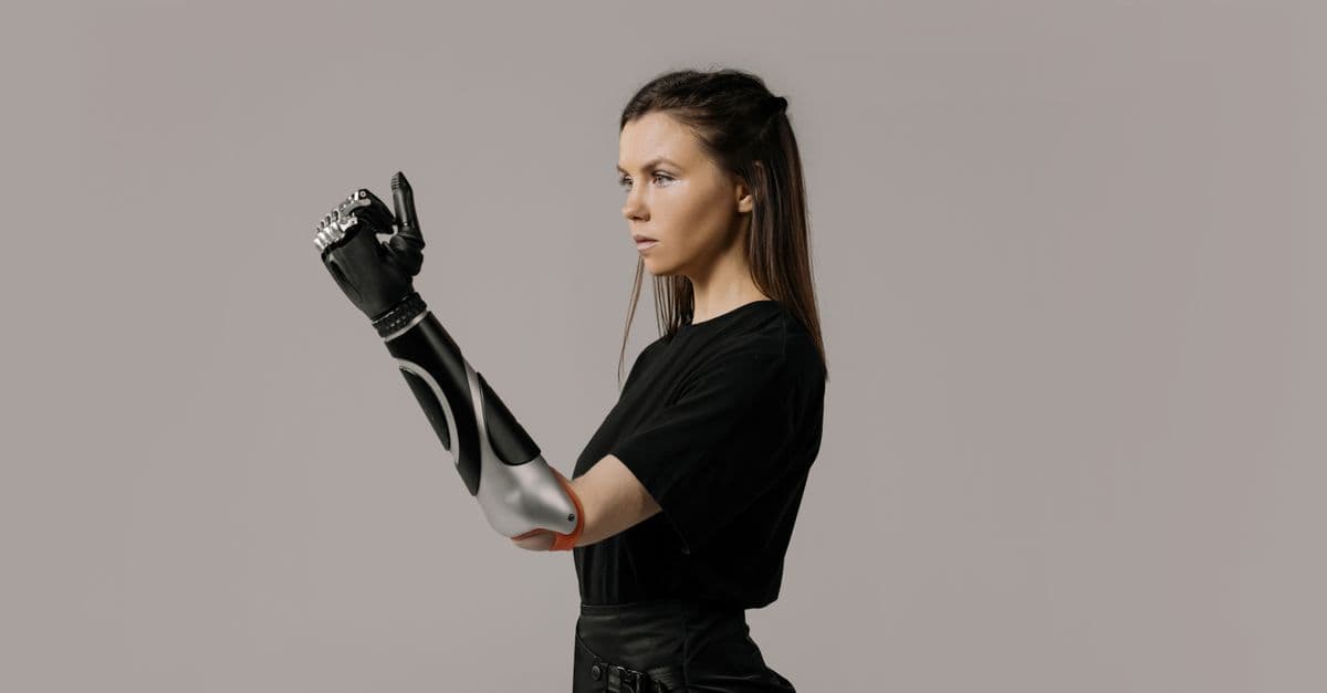 Portrait of a woman with a modern prosthetic arm in a studio setting.