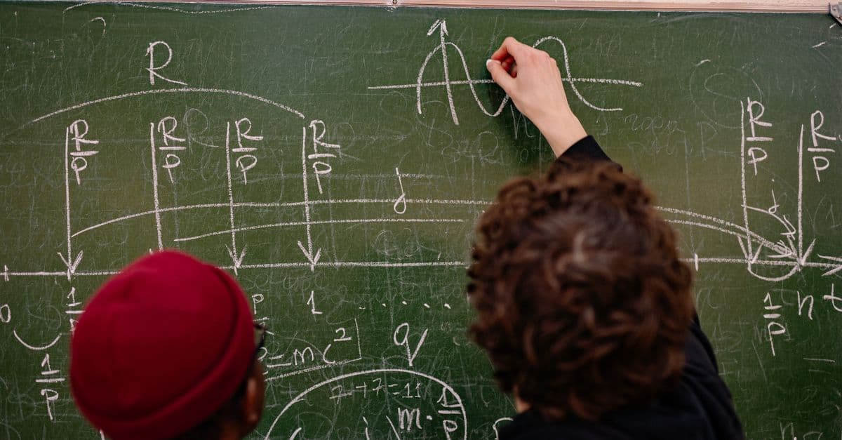 Students working together on complex math problems on a chalkboard.