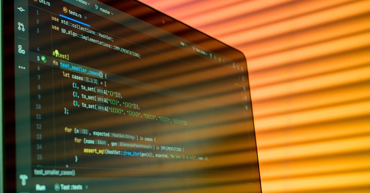 Blurry close-up of a computer screen displaying code with orange lighting.