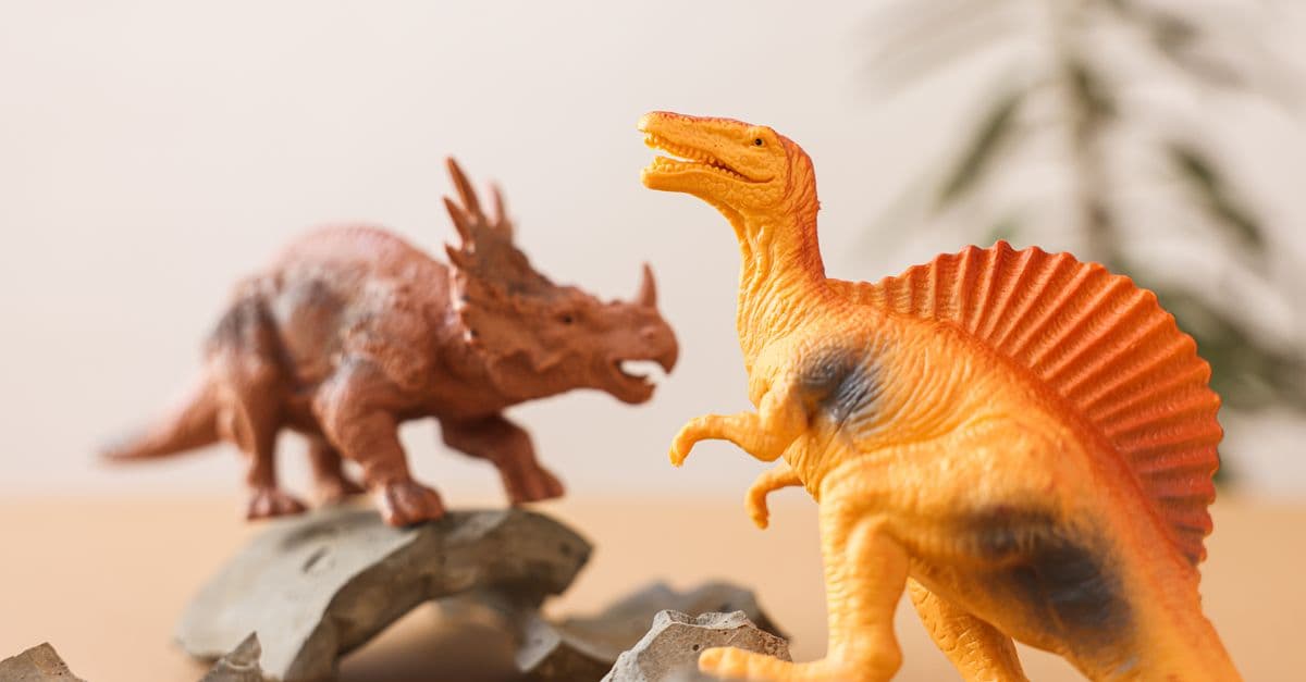 Close-up of dinosaur toys on a tabletop with broken shards, evoking prehistoric play.