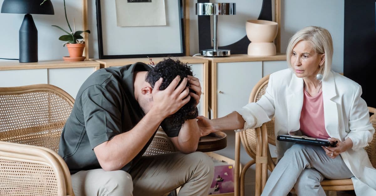 A supportive therapist provides comfort during a counseling session in a cozy office.