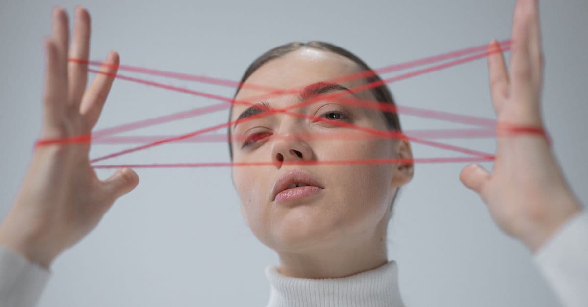 Creative portrait of a woman interacting with a red string art concept.