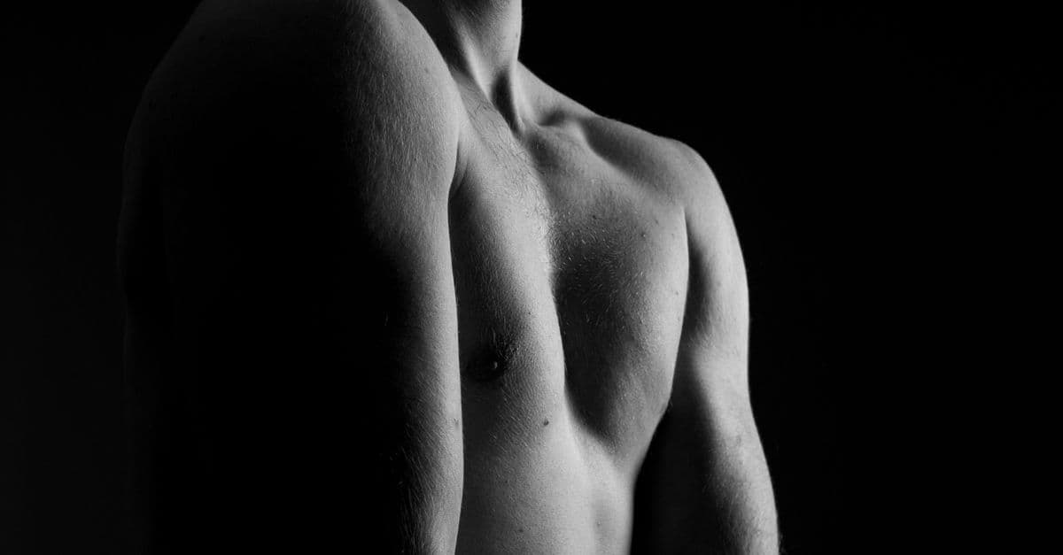 Artistic grayscale photo highlighting a shirtless male torso, emphasizing light and shadow.