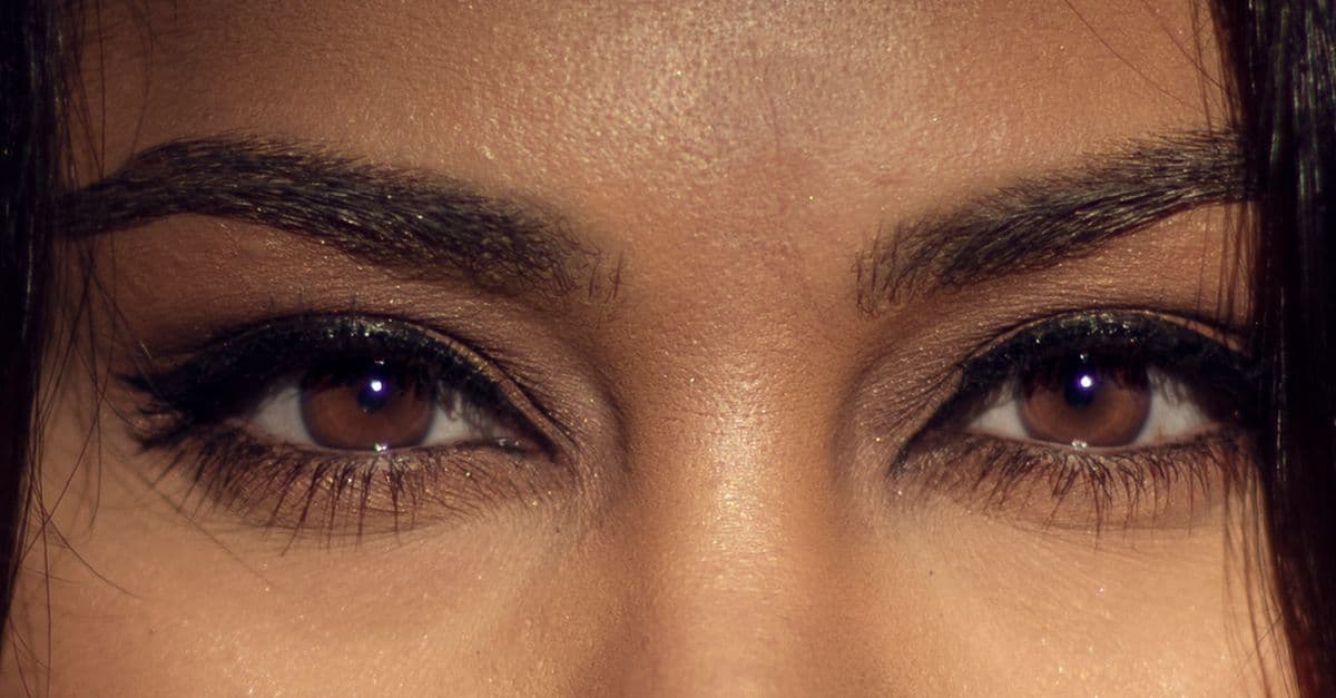 A detailed close-up of a woman's brown eyes highlighting makeup and natural beauty.