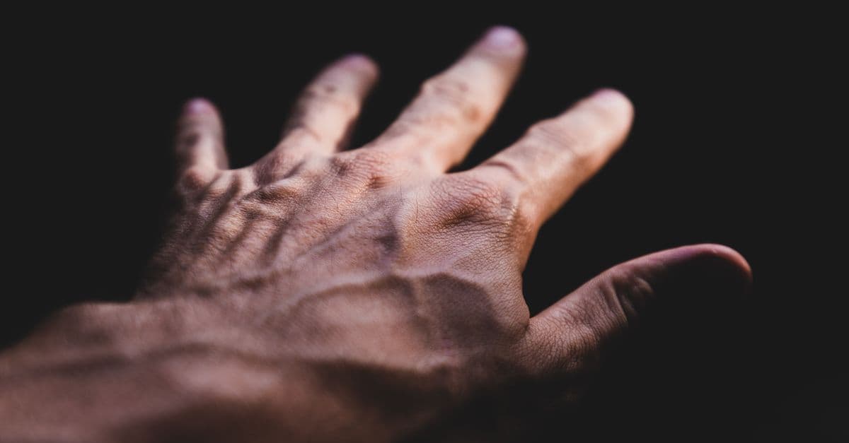 Detailed image of a human hand showing prominent veins against a dark background.