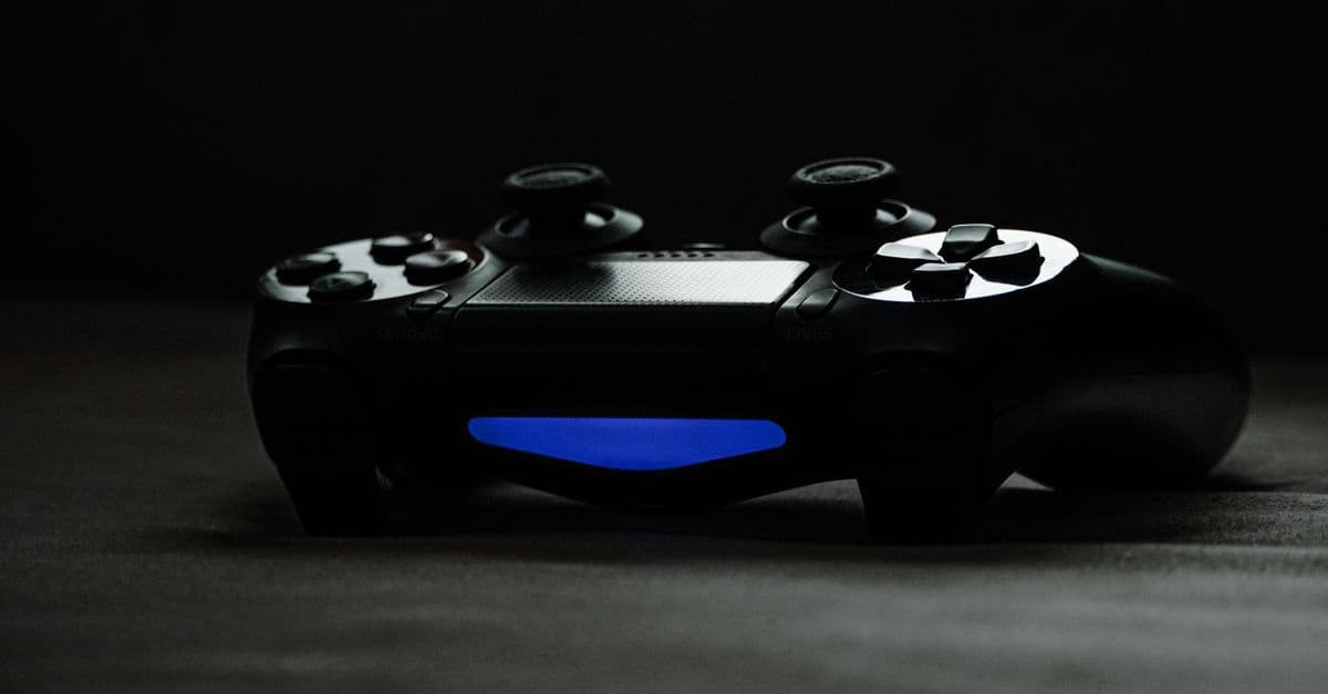 Black gaming controller with glowing blue light on a dark surface, perfect for tech-themed projects.