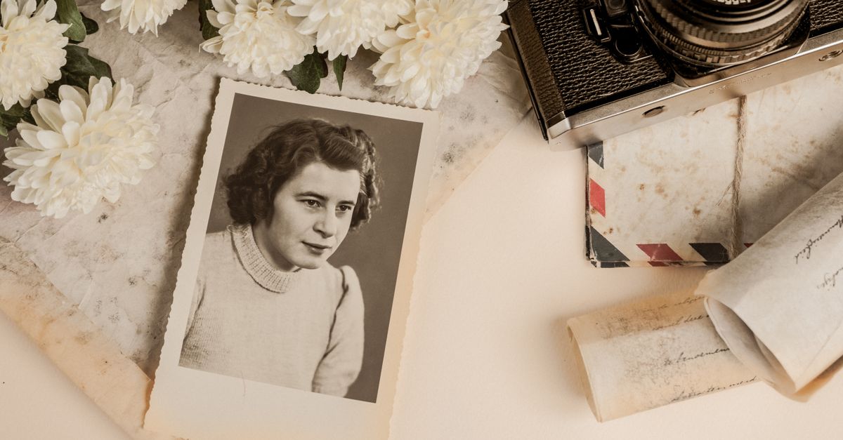 A nostalgic composition featuring a vintage photograph, old camera, and white flowers.